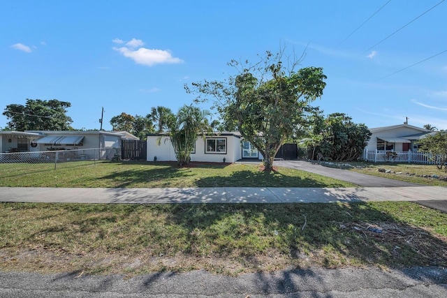 view of front facade featuring driveway, fence private yard, and a front yard