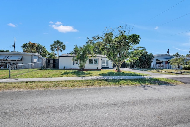 view of front of house featuring driveway, fence private yard, and a front lawn