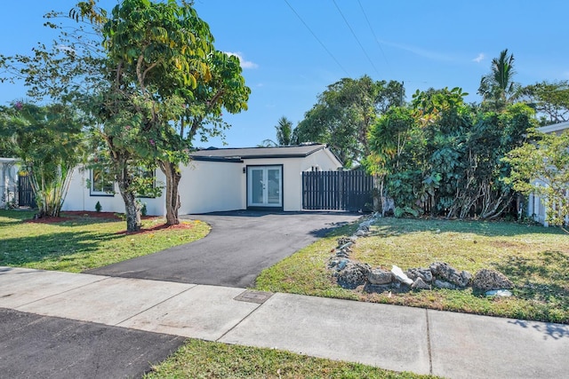 view of front of home with stucco siding, a front yard, driveway, and fence