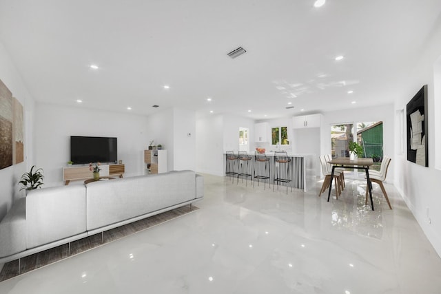 living area with visible vents, recessed lighting, and marble finish floor