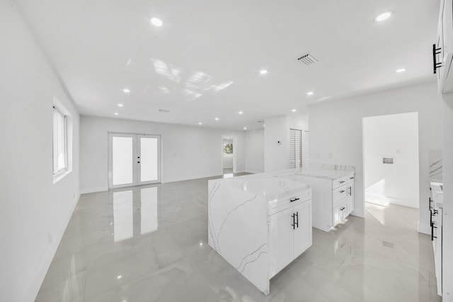 kitchen featuring visible vents, light stone countertops, marble finish floor, and white cabinetry