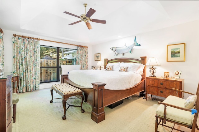 carpeted bedroom with a tray ceiling and ceiling fan