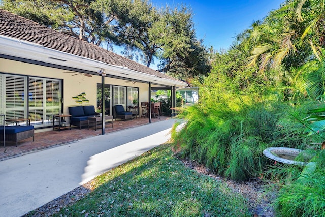 view of yard featuring ceiling fan, an outdoor hangout area, and a patio