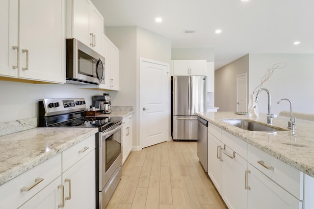 kitchen with light stone counters, sink, white cabinets, and appliances with stainless steel finishes