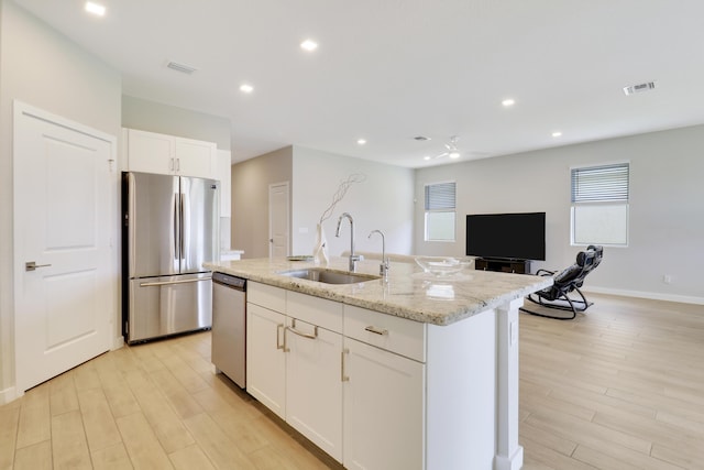 kitchen with white cabinets, light hardwood / wood-style flooring, ceiling fan, an island with sink, and stainless steel appliances