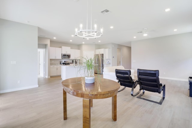 living room with ceiling fan with notable chandelier and light wood-type flooring