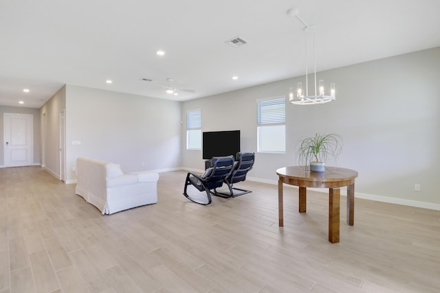 living room featuring light hardwood / wood-style floors and ceiling fan with notable chandelier