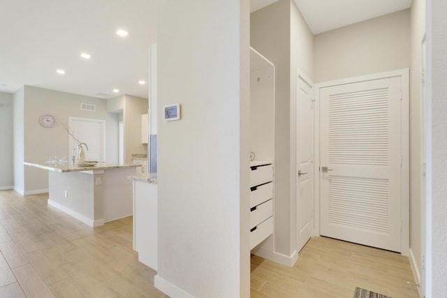 hallway with light wood-type flooring and sink