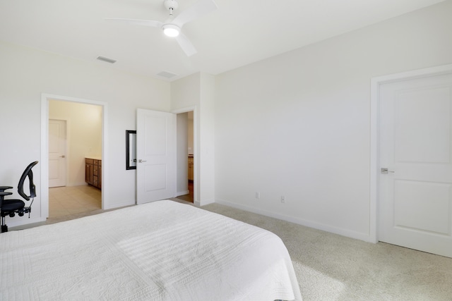 bedroom with ceiling fan, ensuite bathroom, and light carpet