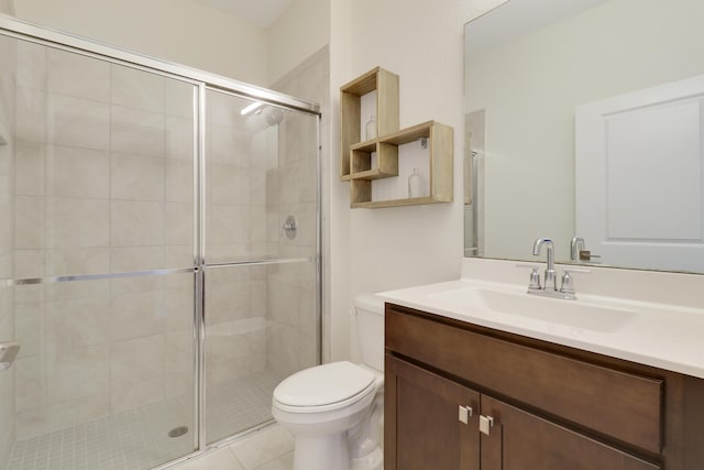 bathroom featuring tile patterned flooring, vanity, toilet, and an enclosed shower