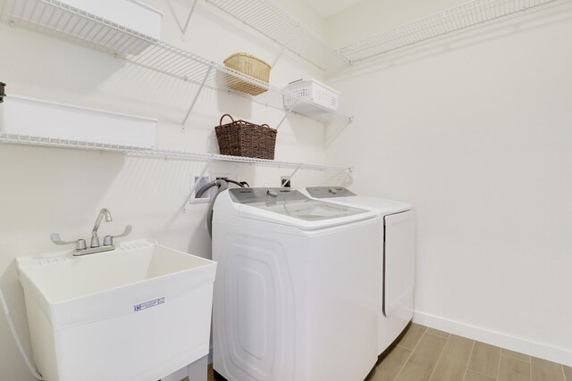 laundry area featuring washer and dryer, sink, and light hardwood / wood-style flooring