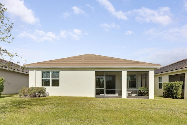 rear view of house featuring a sunroom and a lawn