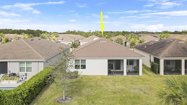 rear view of house featuring a sunroom and a yard