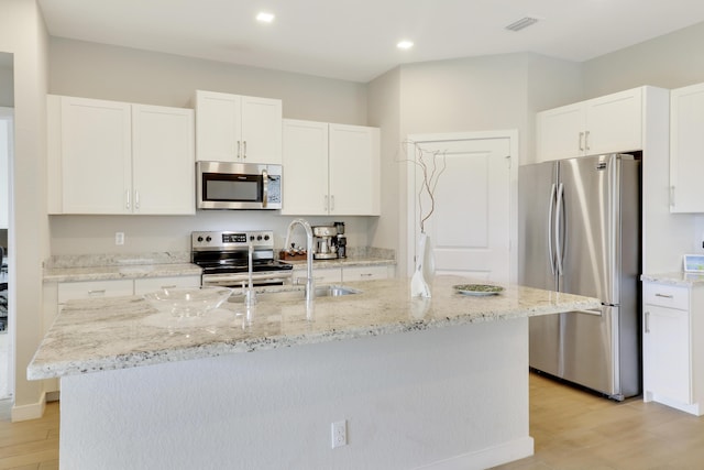 kitchen with a center island with sink, light hardwood / wood-style floors, white cabinets, and stainless steel appliances