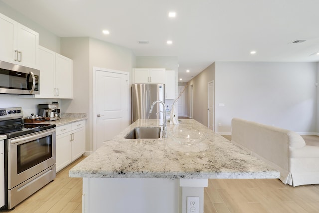 kitchen with stainless steel appliances, light hardwood / wood-style flooring, a kitchen island with sink, and sink