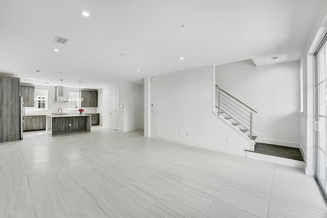 unfurnished living room featuring light tile patterned flooring and sink