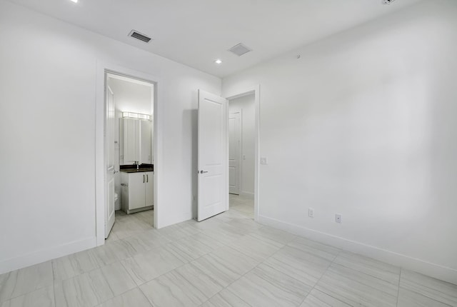 unfurnished bedroom featuring ensuite bath and sink