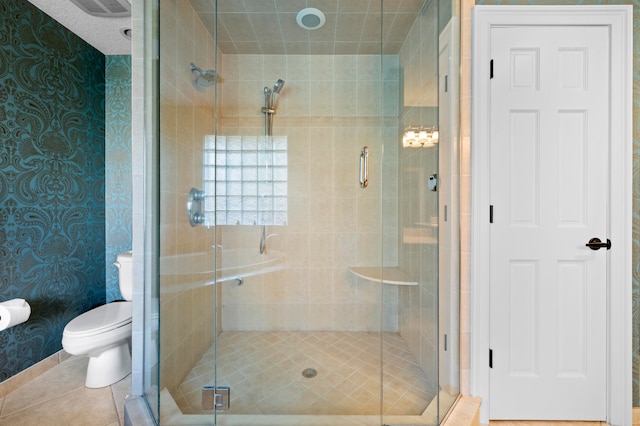 bathroom with tile patterned flooring, toilet, and a shower with shower door