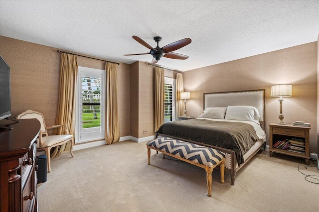 bedroom with ceiling fan, light colored carpet, and a textured ceiling