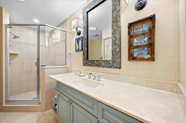 bathroom featuring tile patterned flooring, vanity, a textured ceiling, and a shower with shower door