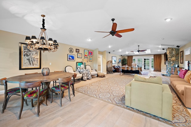 living room with ceiling fan with notable chandelier, light wood-type flooring, and lofted ceiling