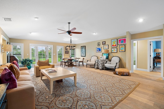 living room with ceiling fan with notable chandelier and light wood-type flooring