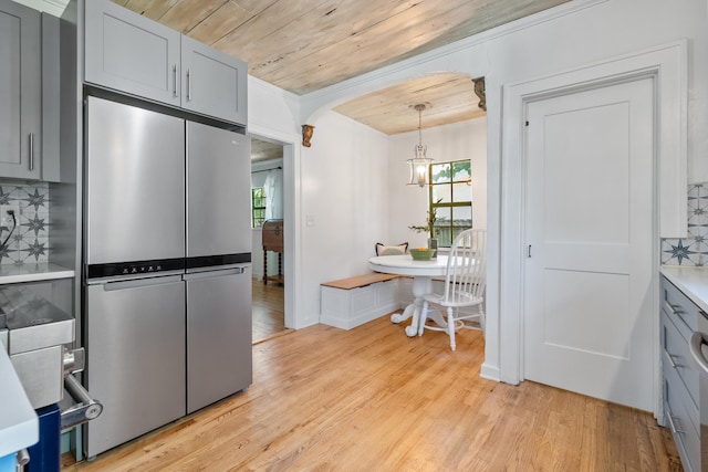 kitchen with stainless steel refrigerator, decorative backsplash, plenty of natural light, and light hardwood / wood-style flooring