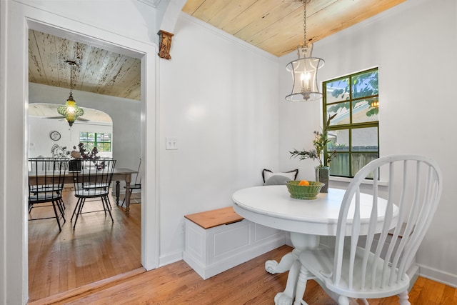 dining area featuring a notable chandelier, wood-type flooring, ornamental molding, and wooden ceiling