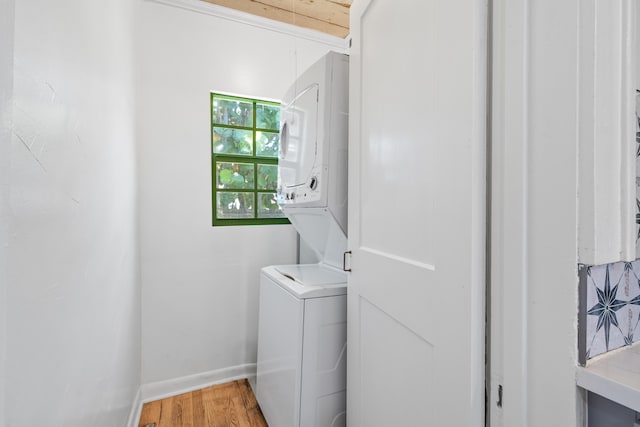 clothes washing area with stacked washer and clothes dryer and hardwood / wood-style flooring