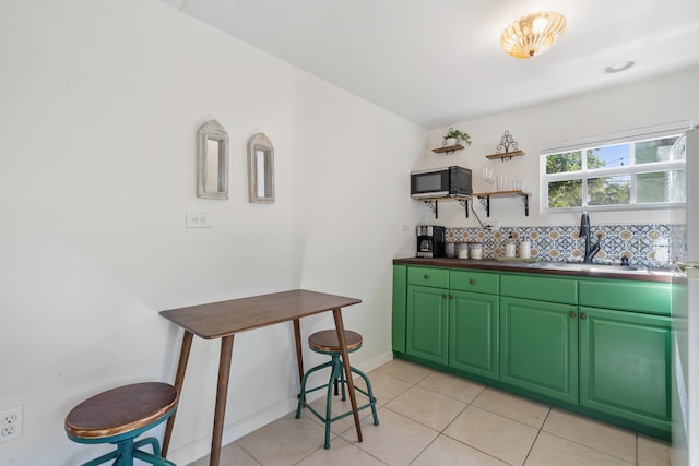 kitchen with green cabinets, sink, and light tile patterned flooring