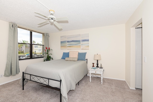 carpeted bedroom with ceiling fan and a textured ceiling