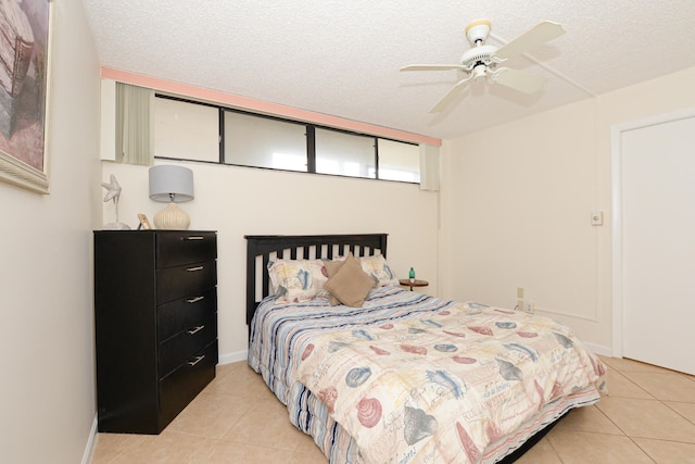 bedroom featuring ceiling fan, light tile patterned floors, and a textured ceiling