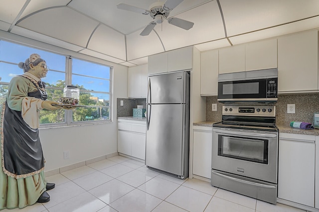 kitchen with white cabinets, decorative backsplash, light tile patterned floors, and stainless steel appliances