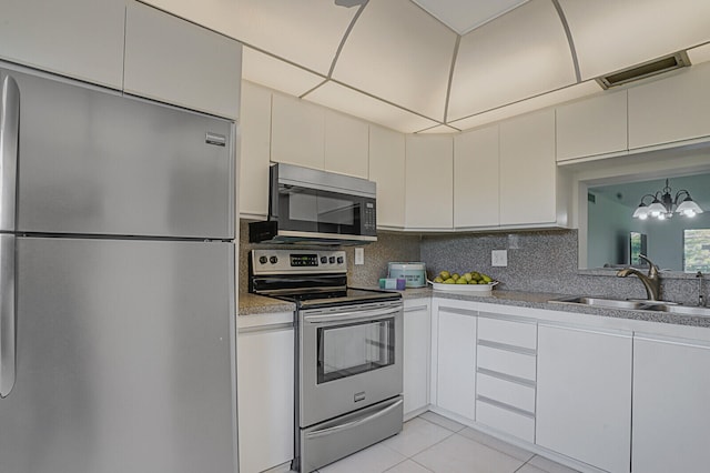 kitchen with stainless steel appliances, sink, an inviting chandelier, white cabinetry, and light tile patterned flooring