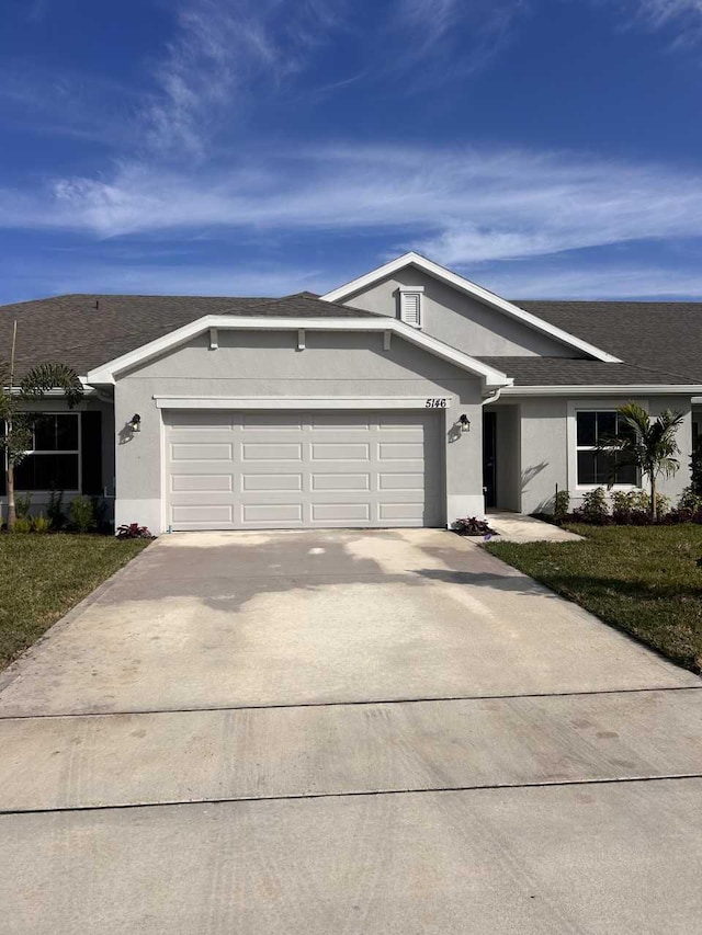 ranch-style house featuring a garage and a front lawn