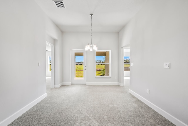 spare room featuring carpet floors and a chandelier