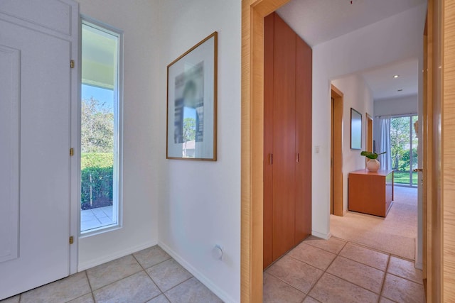 hallway with a healthy amount of sunlight and light tile patterned floors