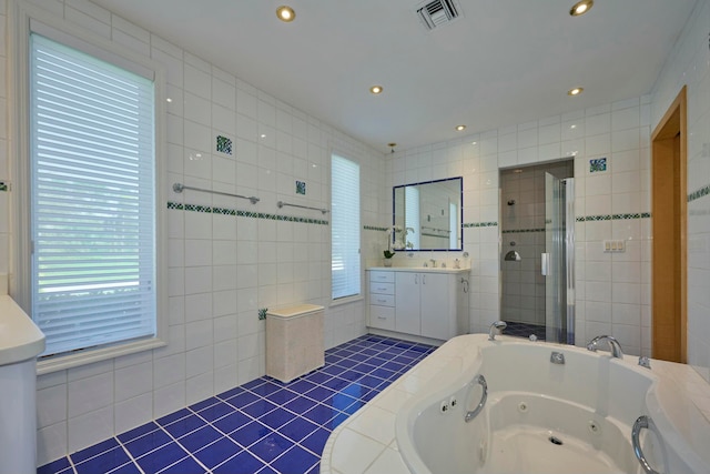 bathroom with tile patterned flooring, vanity, tile walls, and shower with separate bathtub