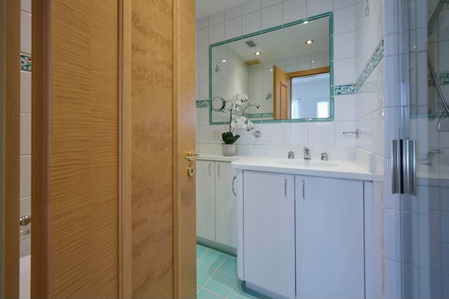 bathroom with an enclosed shower, vanity, tile walls, and backsplash