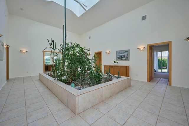 bathroom featuring a skylight, tile patterned flooring, and high vaulted ceiling