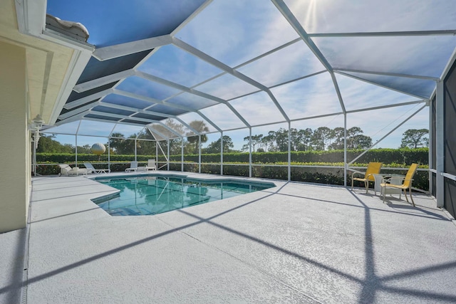 view of swimming pool featuring glass enclosure and a patio area