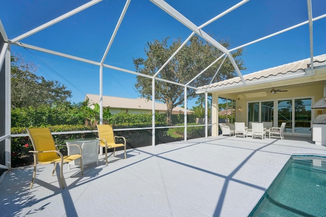 view of pool with glass enclosure, ceiling fan, and a patio area