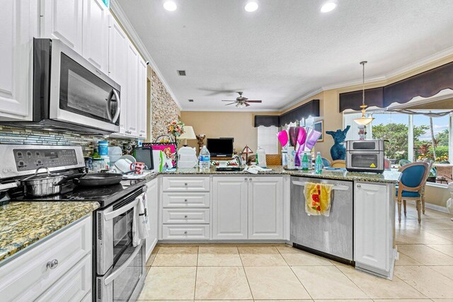 kitchen featuring pendant lighting, white cabinets, ornamental molding, kitchen peninsula, and stainless steel appliances