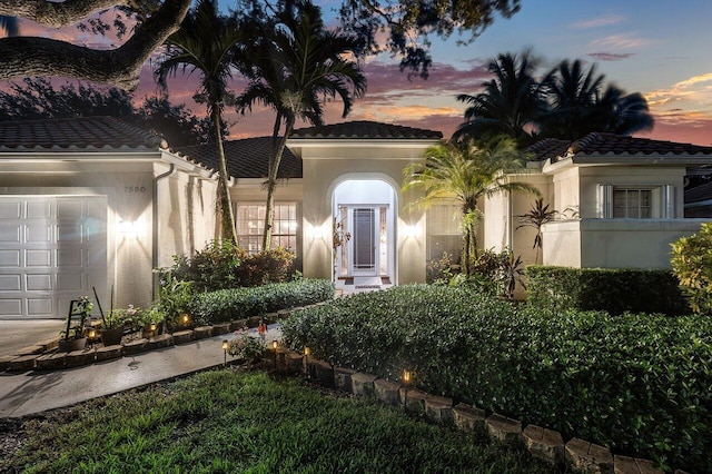 7580 Red River Rd, West Palm Beach, FL 33411 - mediterranean / spanish house with a tile roof, a garage, and stucco siding