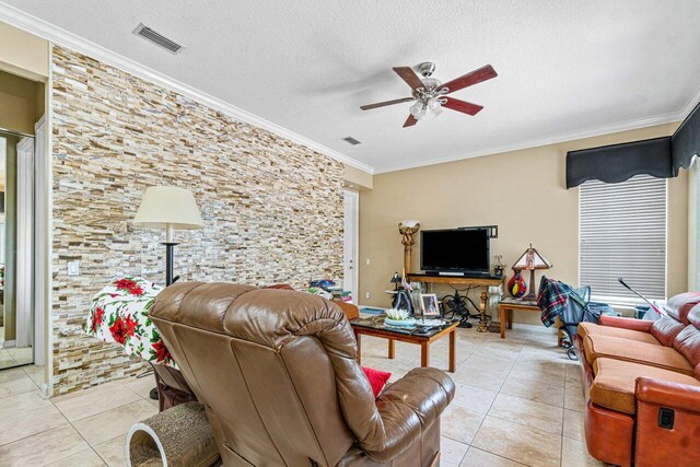 living room featuring ceiling fan, light tile patterned floors, a textured ceiling, and ornamental molding