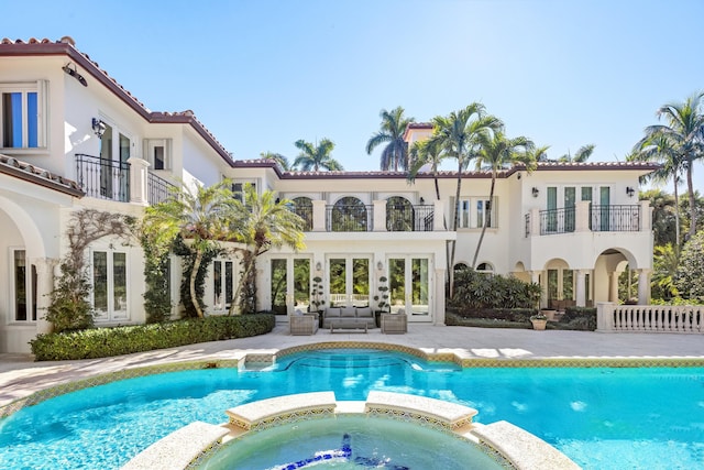 back of property featuring a patio area, a balcony, a swimming pool with hot tub, and outdoor lounge area