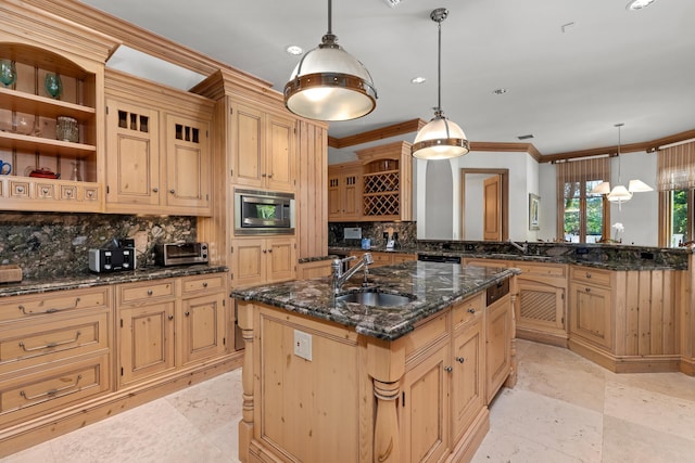 kitchen featuring stainless steel microwave, a kitchen island with sink, pendant lighting, and sink