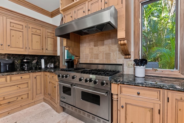 kitchen featuring double oven range, light brown cabinetry, dark stone countertops, backsplash, and ornamental molding