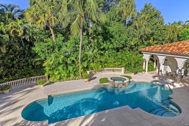 view of swimming pool featuring a patio area, an in ground hot tub, and an outbuilding