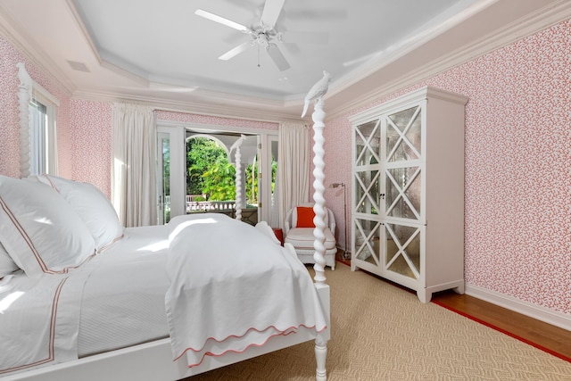 bedroom featuring access to outside, ceiling fan, ornamental molding, wood-type flooring, and a tray ceiling